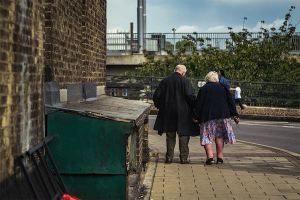 Older man and woman walking down street
