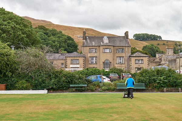 Landscape of hill and older man mowing grass