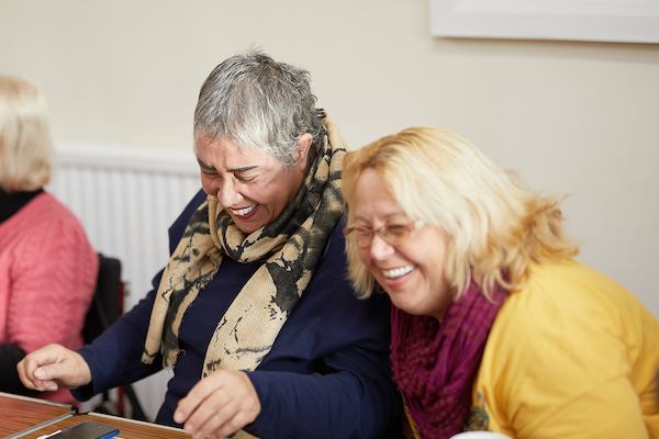 two women volunteers laughing mid-conversation