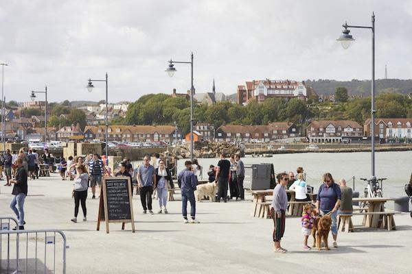 view of a sunny seaside pier with people enjoying the sunshine