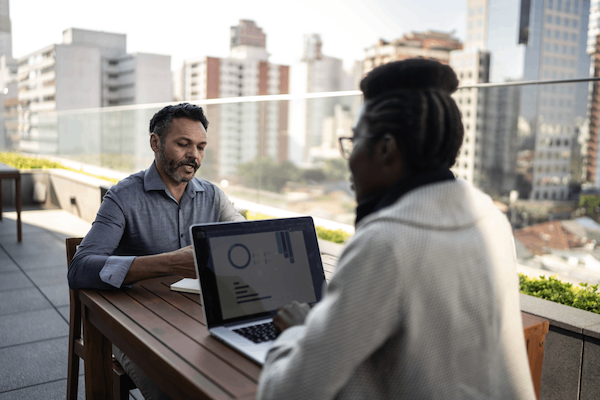 Two office employees sit outside, working together