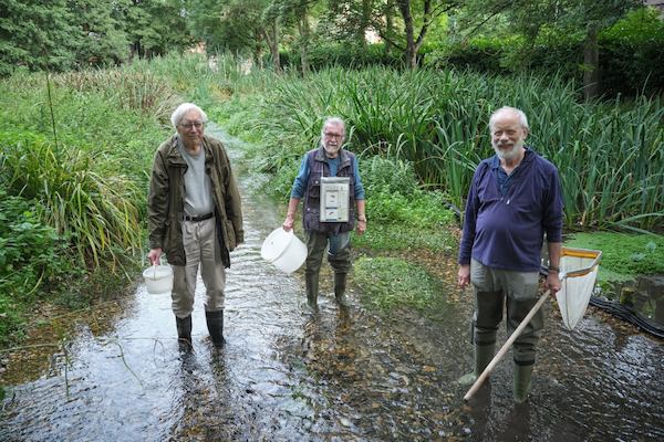 A group of older male volunteers cleaning a river
