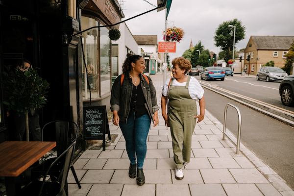 A younger woman and an older woman walk down a high street together