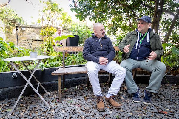 two men sitting and talking outside