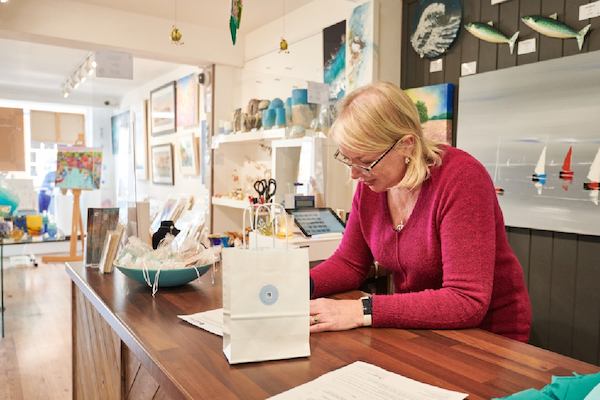 older woman filling in a form behind a till