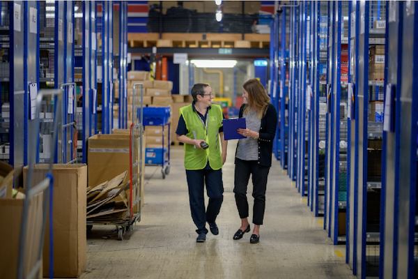two older women walking together in a warehouse