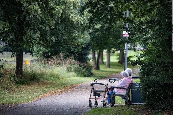 two older people sat on a bench outside