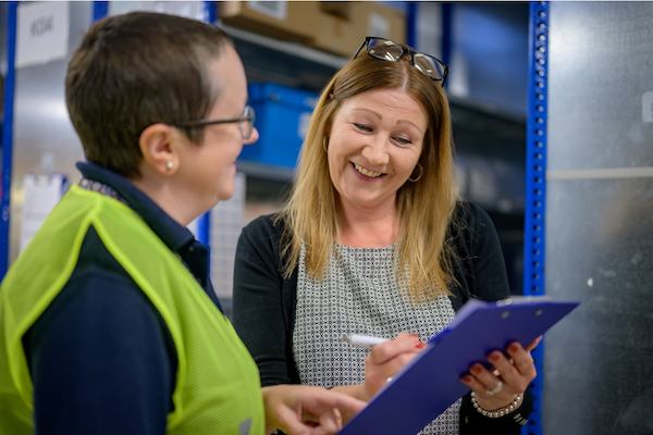 two older women writing on a clip board and talking