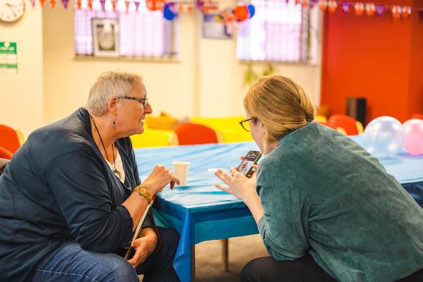 Two women talking and looking at a phone
