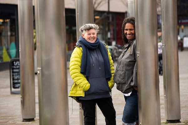 Two older women leaning against columns outside