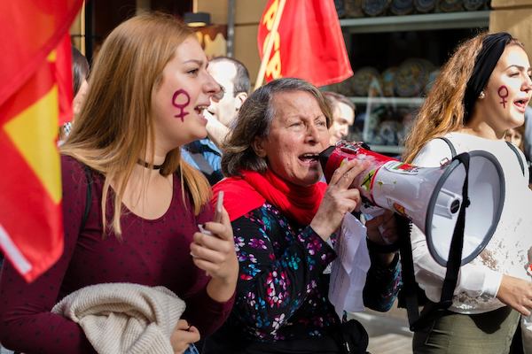 Three women with flags and megaphones at a protest