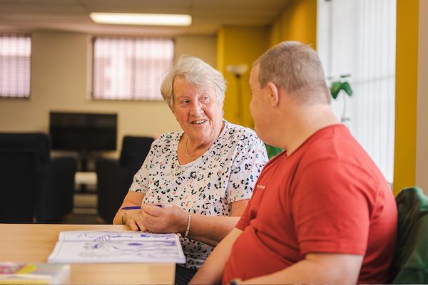 Two older people sitting down and chatting