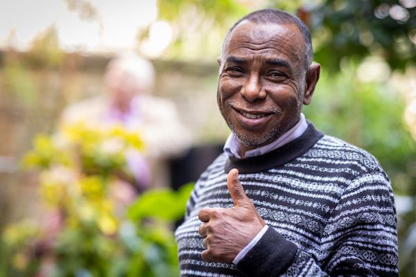 Man in a garden smiling giving a thumbs up at the camera