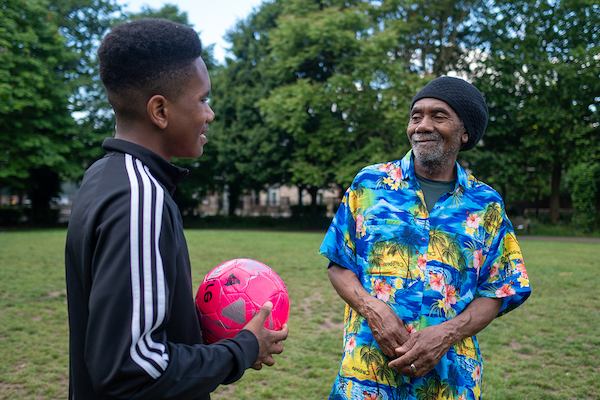 Older man playing football with his son
