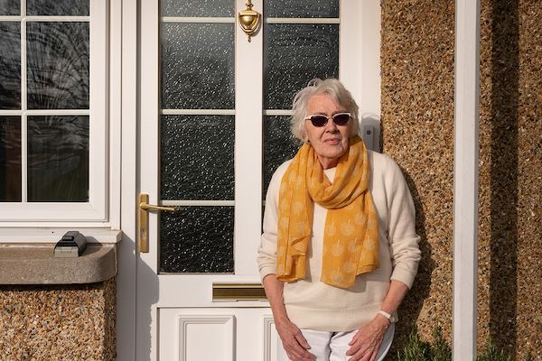 Older woman standing outside her door