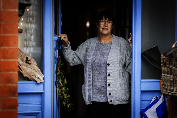 A woman stands in the doorway of her home
