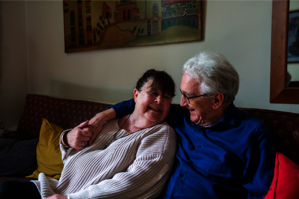 An older couple embrace on a sofa