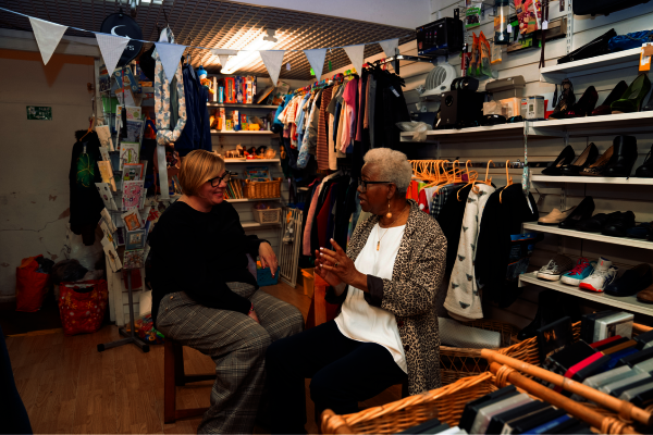 Two older women chat in a charity shop
